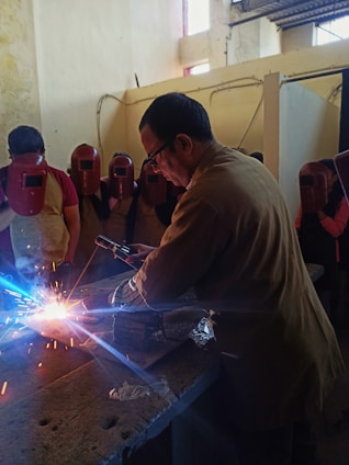 A group of students collaborating on a welding project in a workshop.