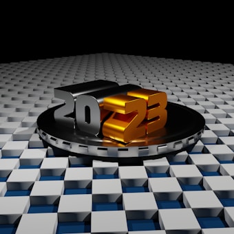 A geometric design featuring large 3D numbers '2023' in metallic colors, with '20' in silver and '23' in gold, set on a circular platform. The background consists of a grid of raised geometric blocks, creating a futuristic and abstract appearance.