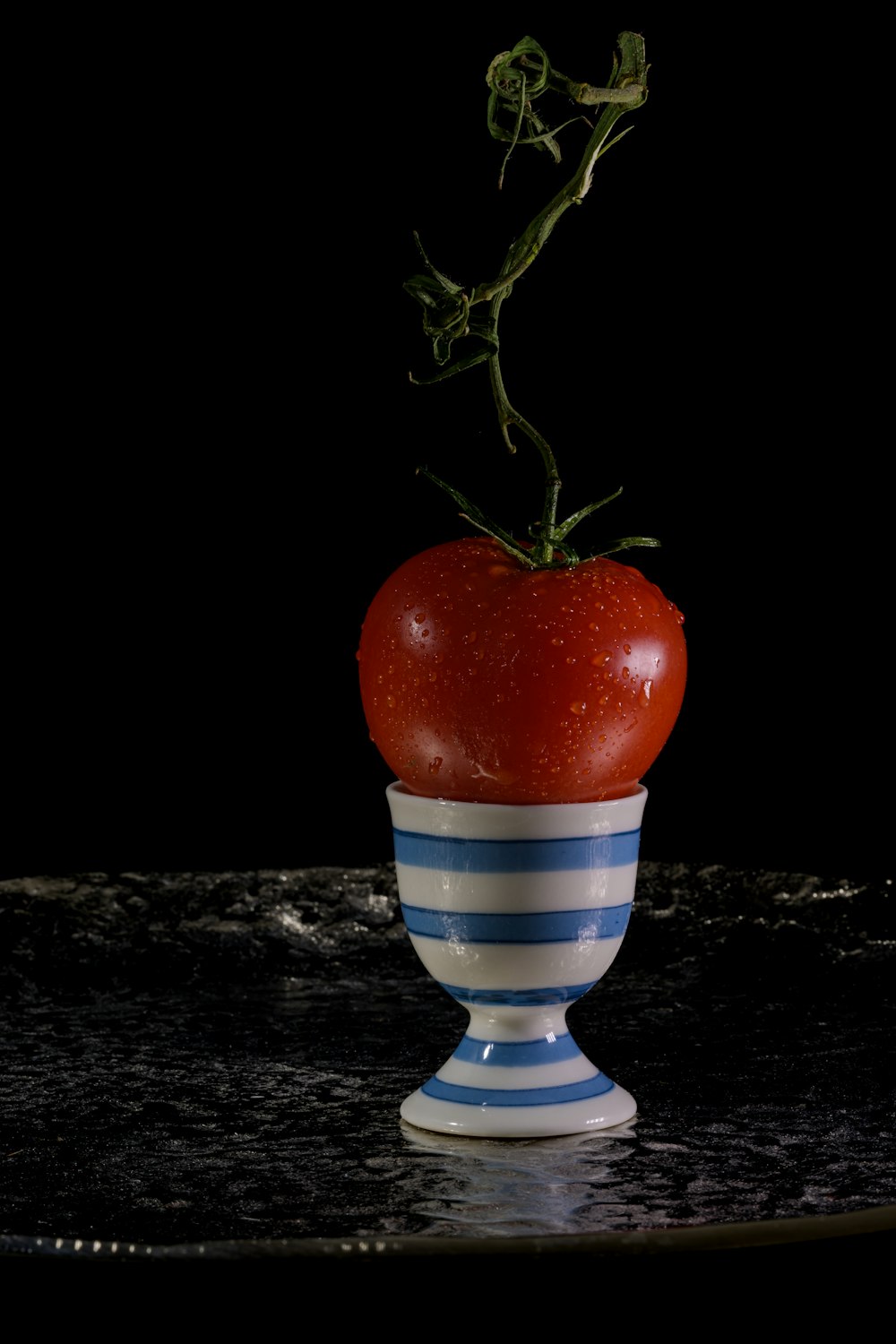 une pomme rouge sur une tasse rayée bleue et blanche