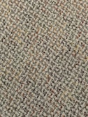 A close-up view of a textured carpet with a speckled pattern. The surface consists of tightly woven loops in various colors, predominantly gray, with interspersed specks of red, orange, yellow, and green.