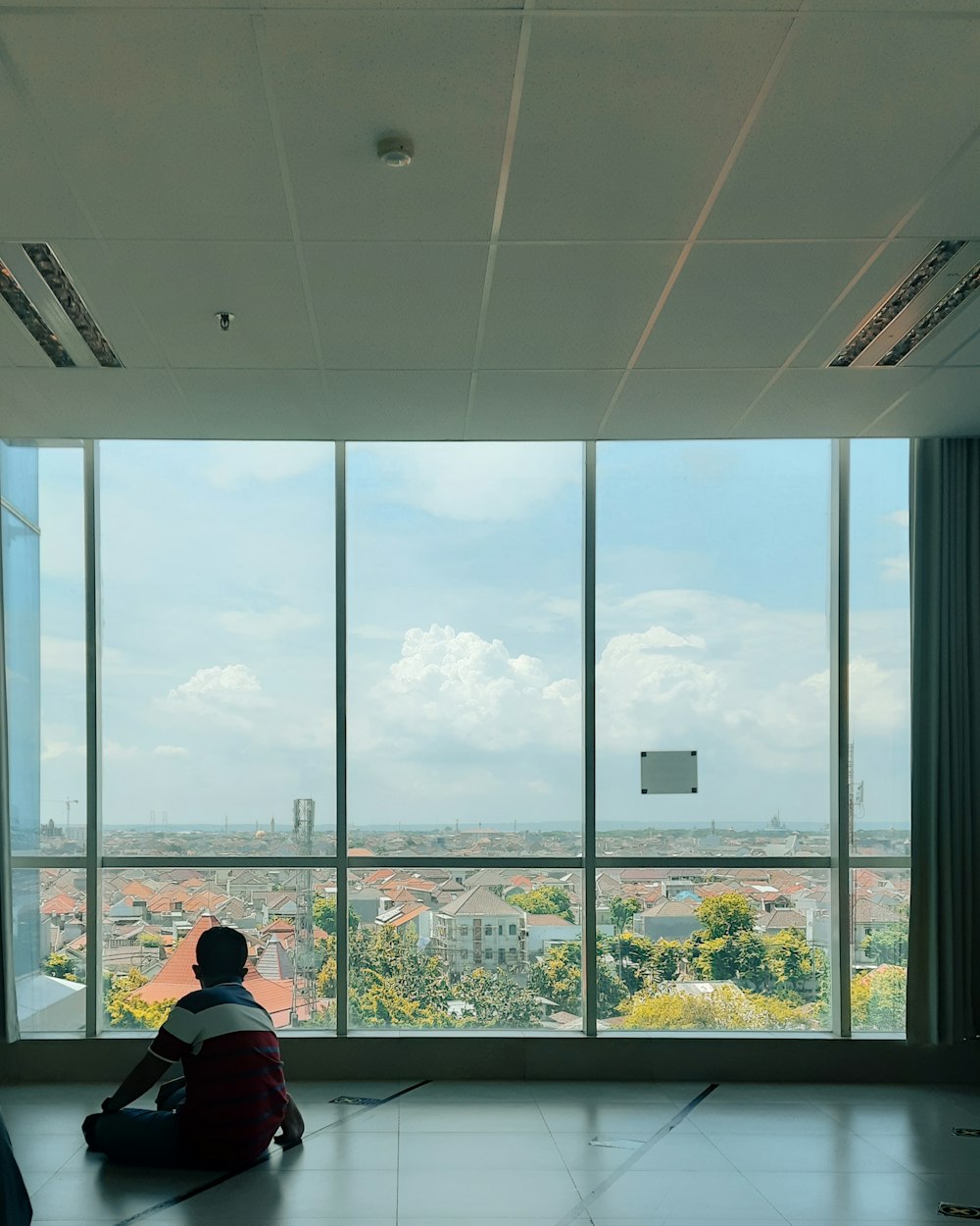 a person sitting in a room looking out a window at a city