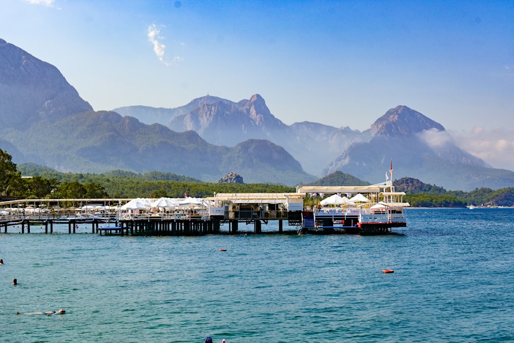 a dock with boats and buildings by a body of water with mountains in the background