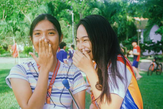 A lively group of young women laughing together outdoors in a park with violet accents.