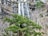A scenic waterfall surrounded by lush green forest and flowing river.