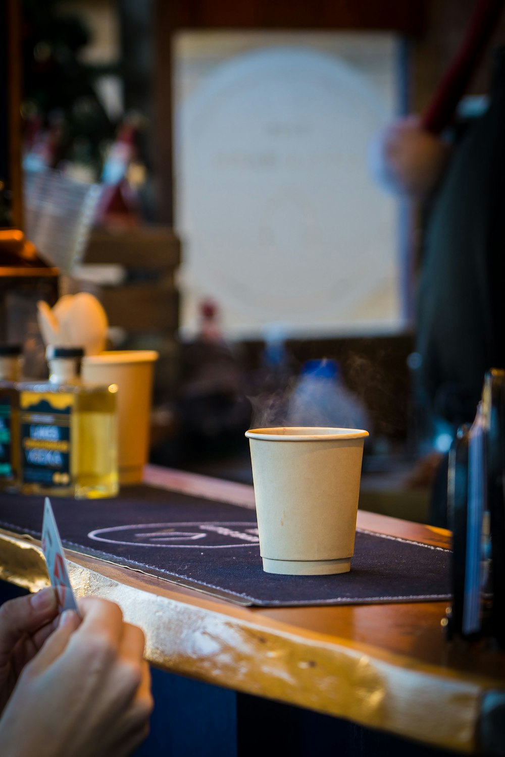 a hand holding a phone next to a cup of coffee