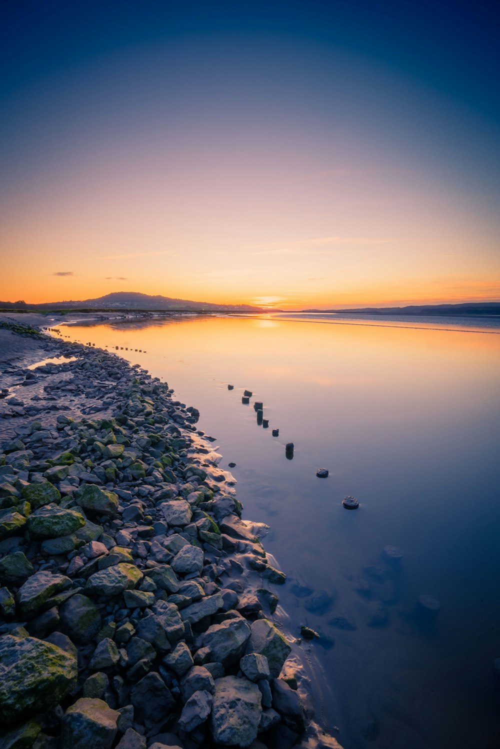 a rocky beach with a body of water in the background photo – Free Uk Image  on Unsplash