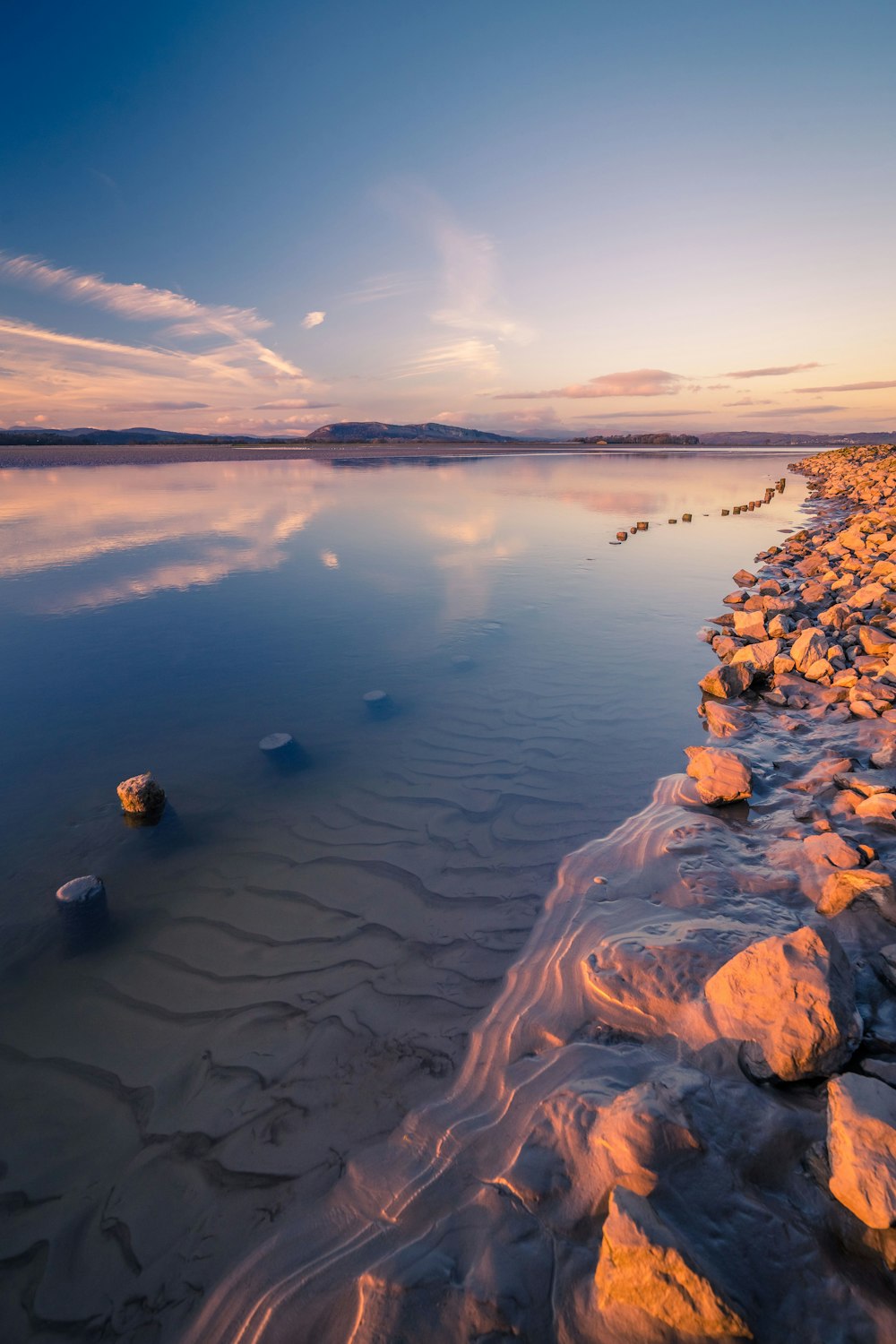 a body of water with rocks and a sunset