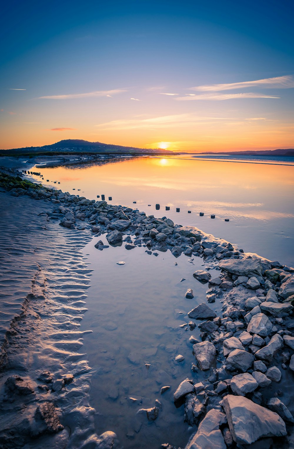 a body of water with rocks and a sunset