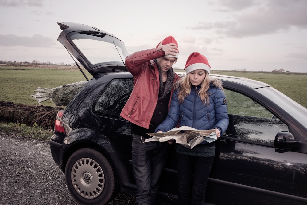 a man and woman standing in front of a car with a large fish in the trunk