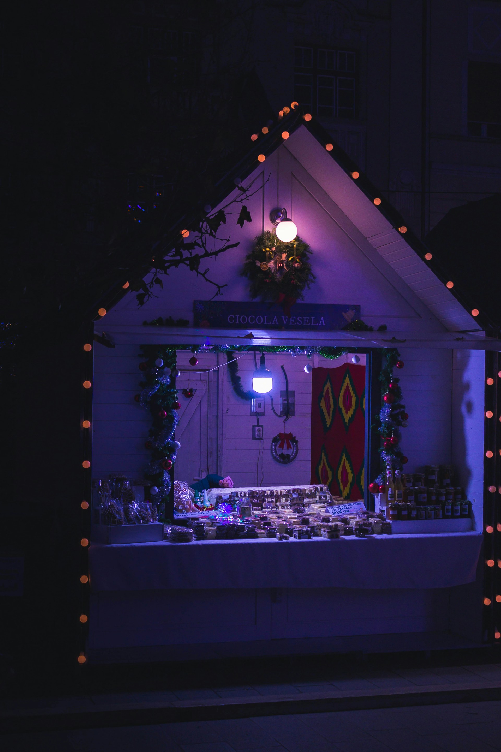A warmly lit Christmas market stall in Moralzarzal, decorated with festive lights and ornaments.