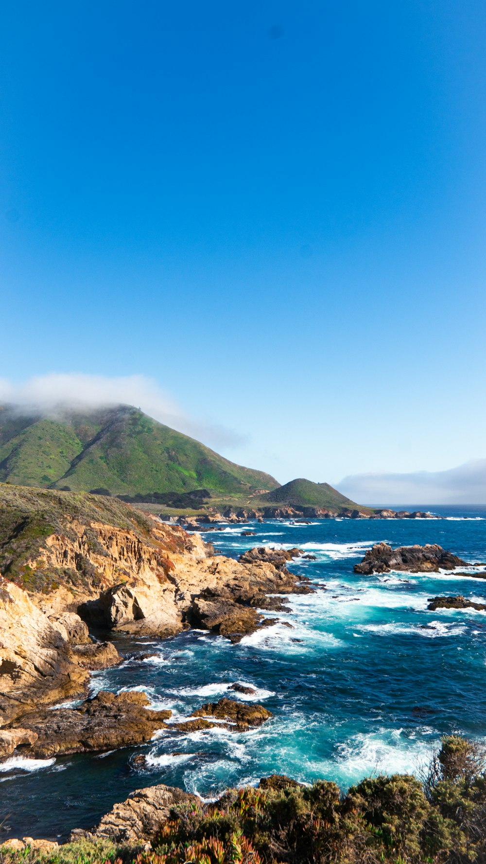 a rocky beach with a body of water and a mountain in the background