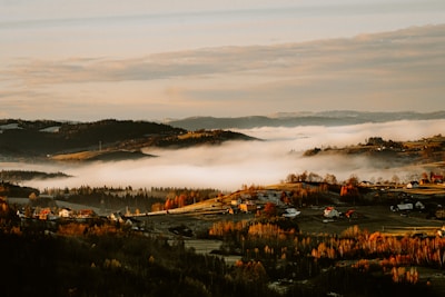 Aerial view of rolling hills dotted with homes and farmland in early morning light.