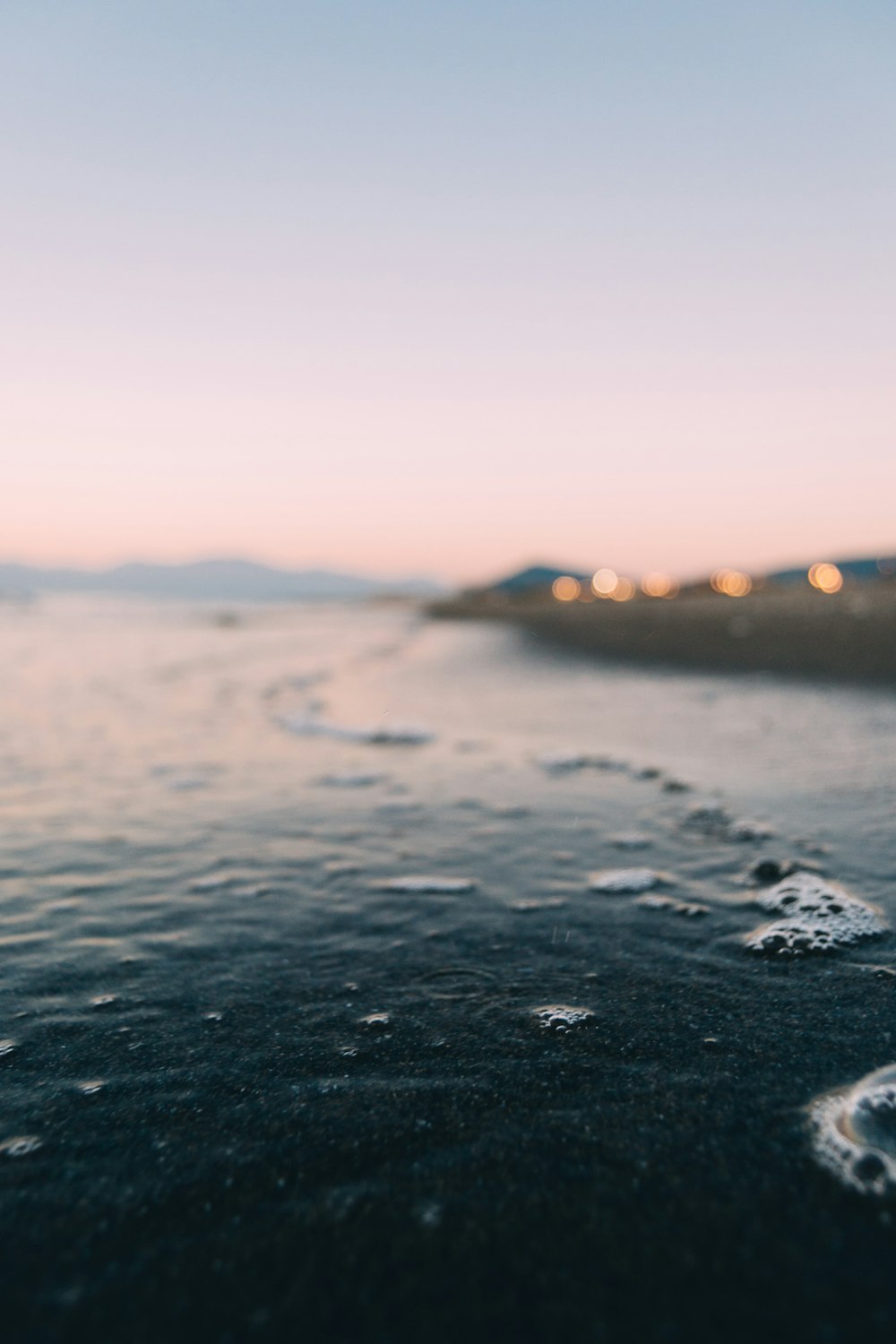 a body of water with ice and a city in the distance