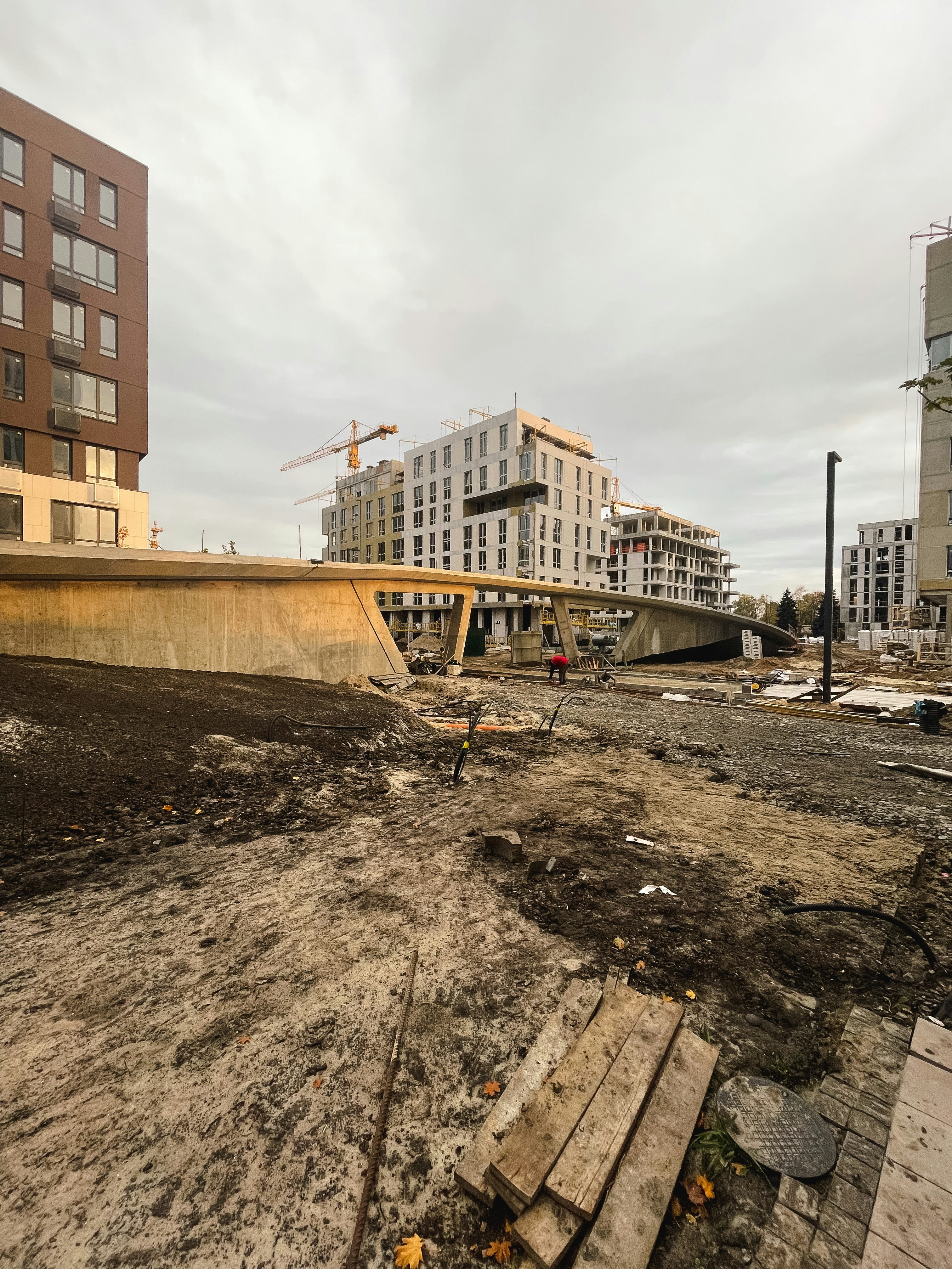 Civil engineering site development, graded land with construction equipment, overcast sky, neutral tones