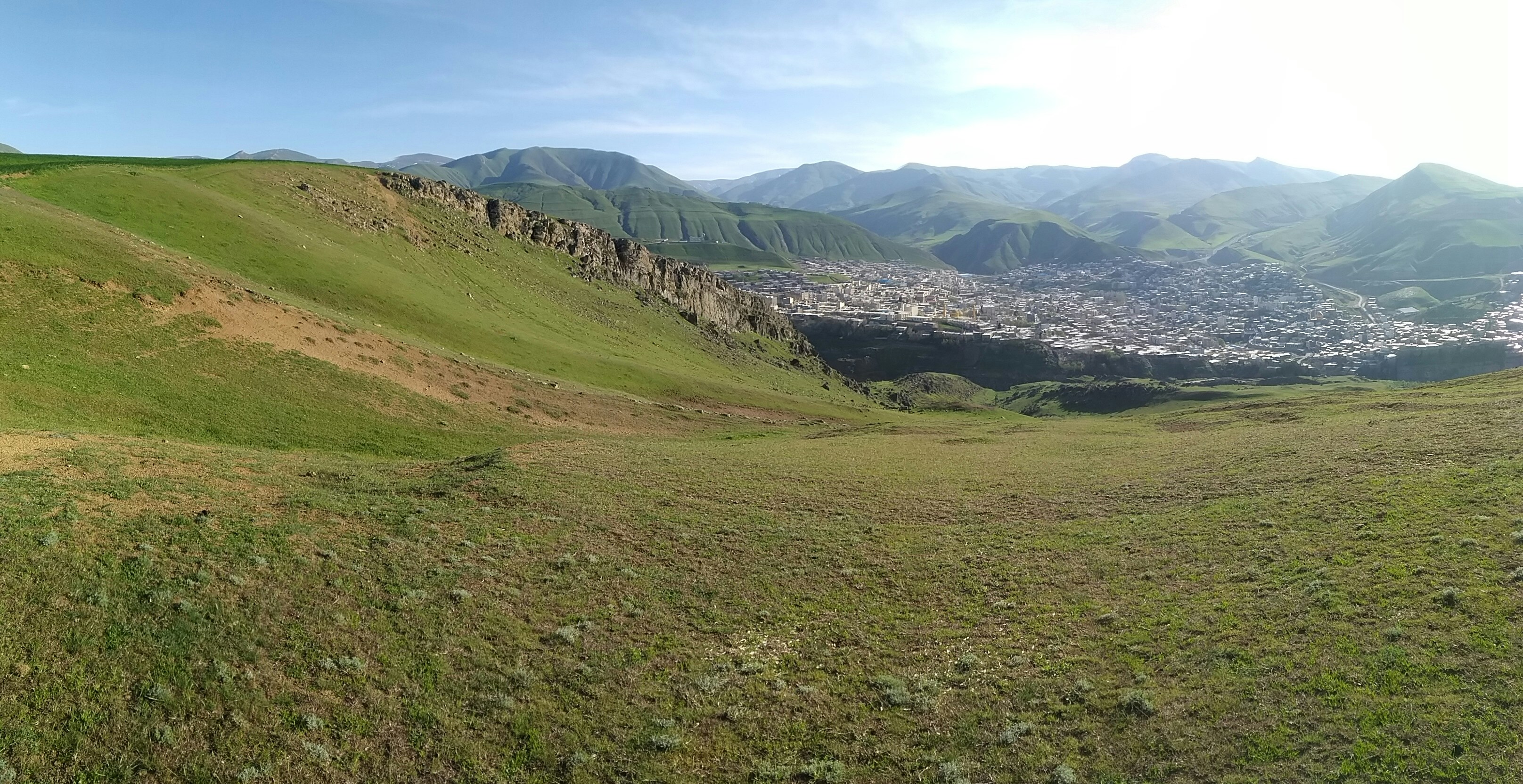 a grassy hill with a town in the distance