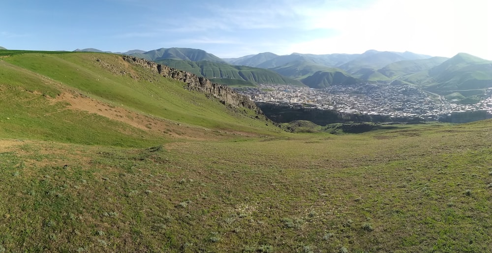 a grassy hill with a town in the distance