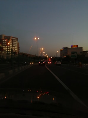 A tow truck driving through a city street at dusk with illuminated signs.