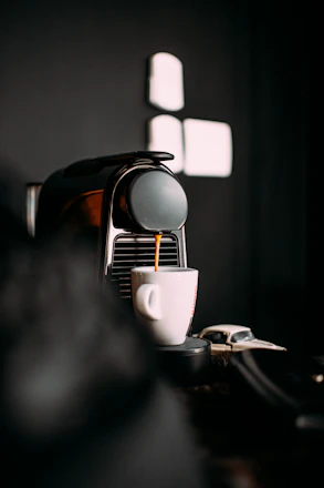 A sleek vending machine dispensing a steaming cup of coffee in a modern office setting.