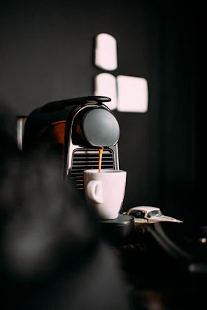 A sleek espresso machine steaming a fresh cup of coffee on a clean white counter.