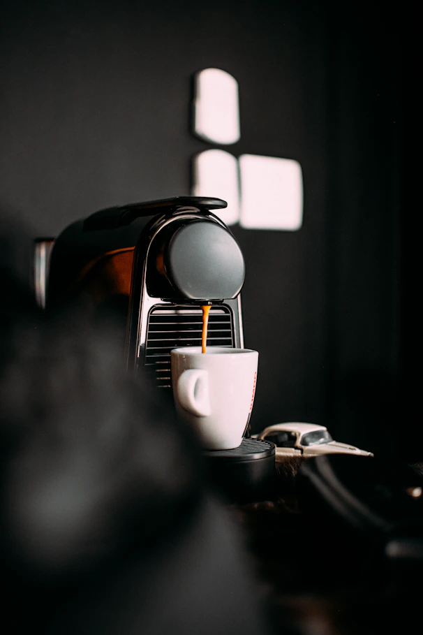 A sleek espresso machine steaming a fresh cup of coffee on a clean white counter.