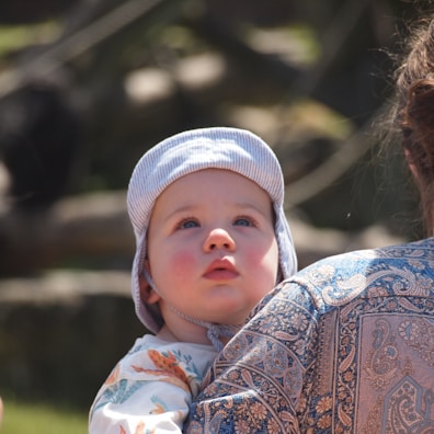 Baby wearing a wide-brimmed hat and sunglasses on a sunny day.