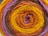 A close-up view of a rolled-up skein of yarn featuring concentric rings of different colors. The yarn is tightly wound, showcasing a vibrant pattern with distinct layers of color.