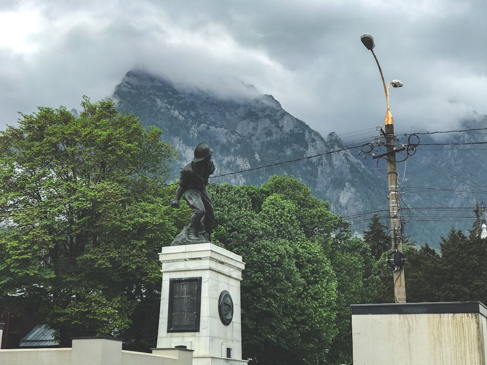 a statue of a person on a pedestal in front of a mountain