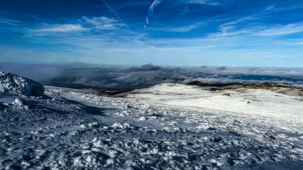 a snowy landscape with a body of water in the distance