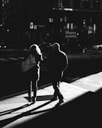 Black and white street photo showing dynamic city life and shadows.
