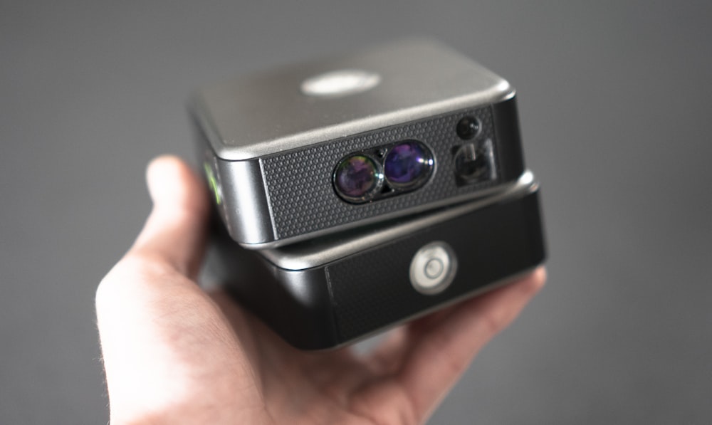 a hand holding a black and silver electronic device