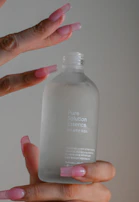 A close-up of a hand holding a sleek bottle of belerys serum with elegant black and gold design.