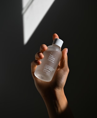 A person holding a glowing vial of fulvic acid liquid with a mysterious dark background