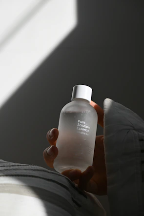 Close-up of hands gently holding a glowing euni product bottle against warm white background.