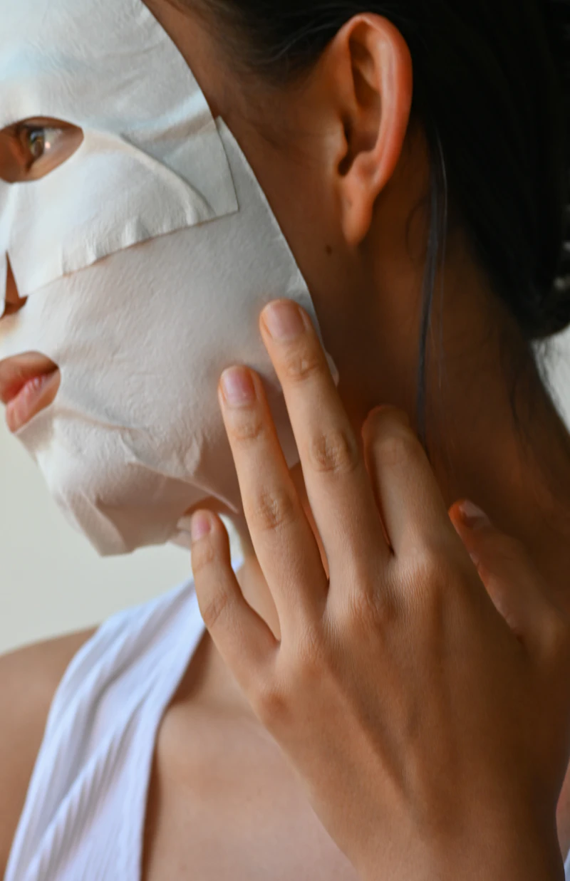 Woman smoothing a hydrating sheet mask over her face