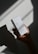 A hand holds a white box labeled 'Pure Solution Essence' against a backdrop with dramatic shadows. The box features minimal design with text in English and another language.