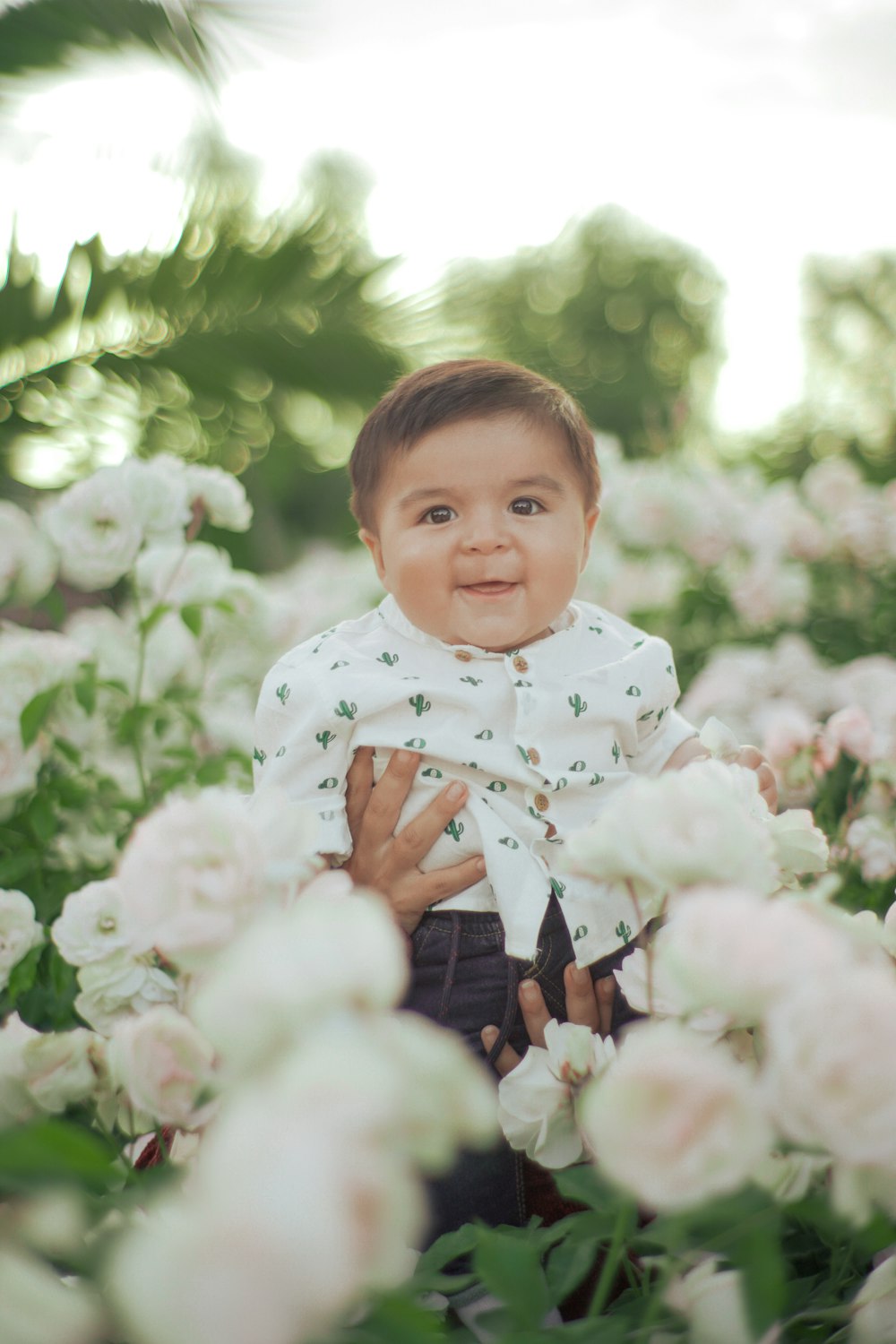 a baby in a white shirt surrounded by white flowers