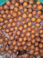 A vibrant platter of Rasgulla balls soaking in syrup, glistening under soft light.