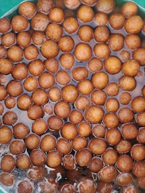 Close-up of sweet rasgulla balls soaking in rich syrup in a rustic bowl.