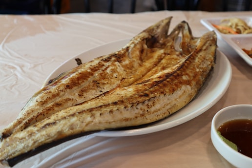 Grilled fish served with tropical sides on a rustic wooden table.