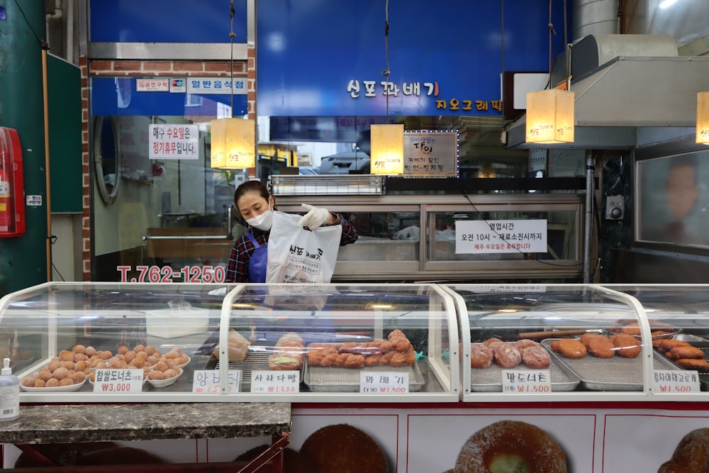 a person standing behind a counter with donuts on it