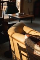 Soft natural light illuminating a forest green velvet armchair beside a gold lamp.
