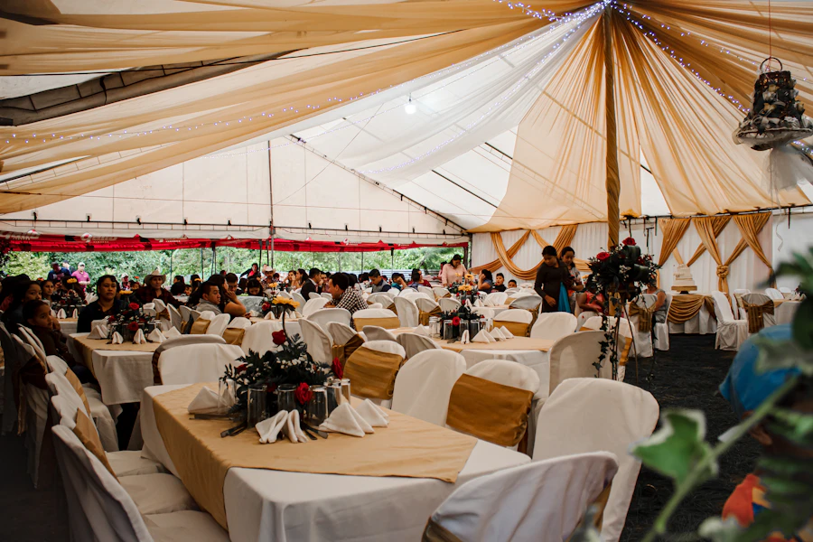 Interior de tenda de evento com mesas postas, toalhas claras e teto forrado de tecido