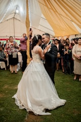 A lively wedding reception with guests dancing and a videographer capturing the moment.