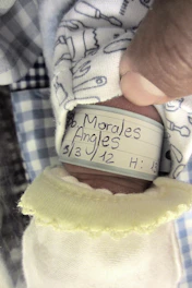 A nurse attentively checking patient ID bracelet in a calm hospital room.