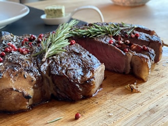 A perfectly seared ribeye steak resting on a wooden board, garnished with fresh rosemary and coarse sea salt.