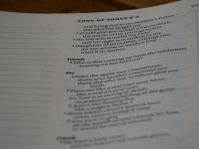 A close-up view of a page from a book, featuring text from the Bible, specifically Song of Songs 8:3. The text is presented in a structured format, with section headings such as 'Friends' and 'She'. The focus is mainly on the center and right side of the page.