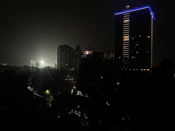 A nighttime cityscape used as a backdrop for an outdoor film shoot under soft blue lighting.