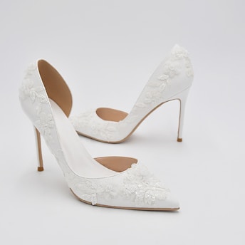 Elegant white high-heeled shoes featuring intricate floral lace details and a pointed toe design.