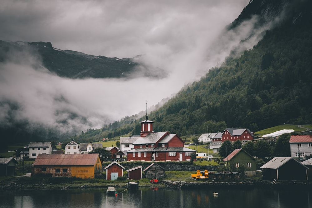 a group of buildings by a body of water with mountains in the background