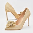 Elegant women’s heels in soft pastel shades placed on a marble surface with delicate floral accents